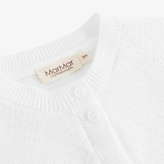 Close-up of a white knit cardigan sweater showing the ribbed collar, white buttons, and a beige MarMar Copenhagen label.