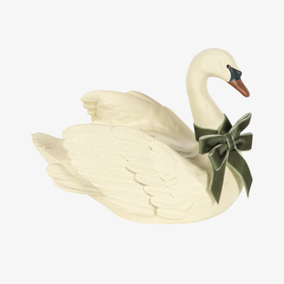 An off-white swan money bank figurine with a dark green velvet bow around its neck and a brown beak, isolated on a light gray background.