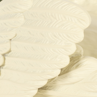 A close-up of a white decorative wing with detailed feather textures and layered scalloped edges.