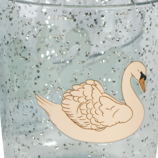 A close-up of a clear tumbler filled with silver glitter and decorated with a cream-colored swan illustration on the front.