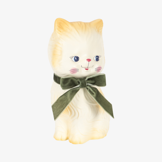 A cream-colored  cat money bank with a dark green velvet bow around its neck, set against a plain light gray background.