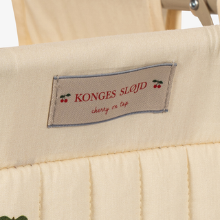 Close-up of a cream-colored quilted fabric product with a stitched label reading 'KONGES SLOJD cherry on top'.