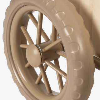 Close-up of a beige plastic toy wheel with a ribbed tread and multi-spoke hub, shown against a plain light background.
