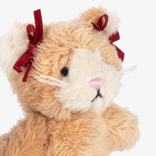 Close up of a plush kitty toy with red bows around the ears. 