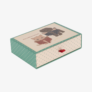 A decorative storage box with a cream-colored top featuring two animal illustrations and the text 'Tiny Teddy Best Friends', with mint green sides patterned with white polka dots and a small red pull tab on the front.