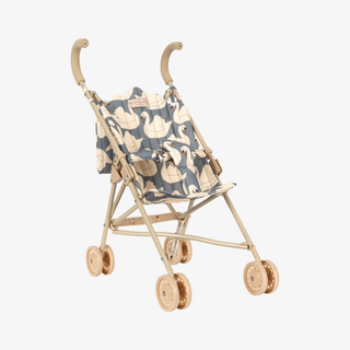 A compact doll stroller with a light beige frame and curved handlebars, featuring a blue-gray fabric seat with a cream swan pattern, shown on a plain light gray background.