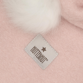 Close-up of a light pink fuzzy textile product with a white faux-fur trim and a sewn-on square label.