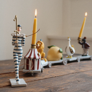 Set of figurines arranged in a train, intended to hold birthday candles in celebreations, featuring a lemon, a goose, a lion. a monkey, and a circus tent. 