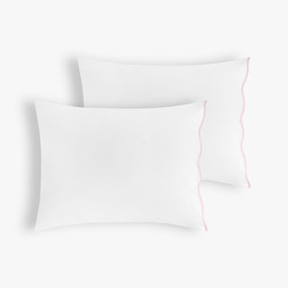 Two white pillows with a thin pink line on a light pink background