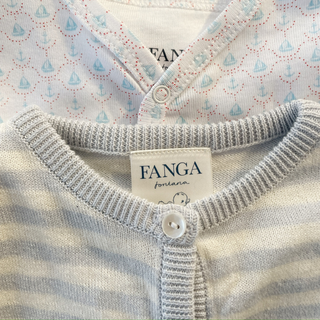 Close-up of a baby outfit with 'FANGA' label on a patterned background