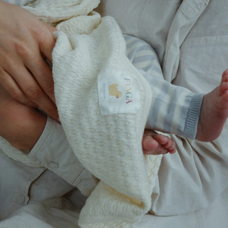 Baby's foot in striped knit pants being held by an adult