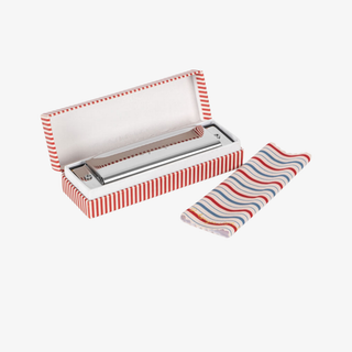 Metal harmonica in a red and white striped case with a matching cloth on a white background