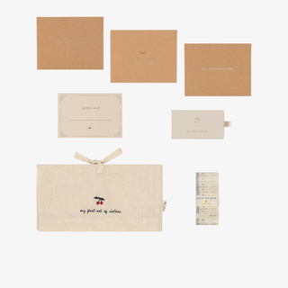 Collection of baby-related items including bags and a milestone card on a white background