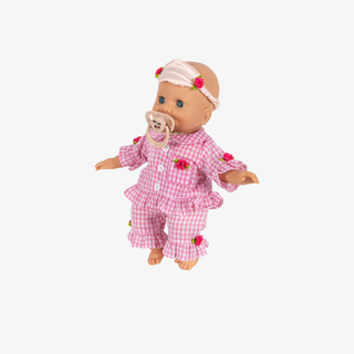 baby doll with pink outfit, pacifier, and eye mask on a white background