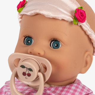 Close-up of a baby doll with a pacifier and floral headband on a white background