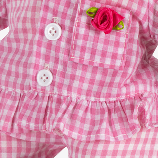 Close-up of a pink and white checkered dress with buttons and a flower detail.