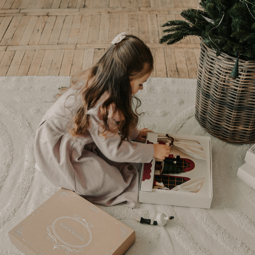 Nutcracker Play Theater wooden box with wooden figurines on the ground with little girl playing with it