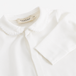A close-up of a white long-sleeve baby top with a scalloped edge Peter Pan collar 