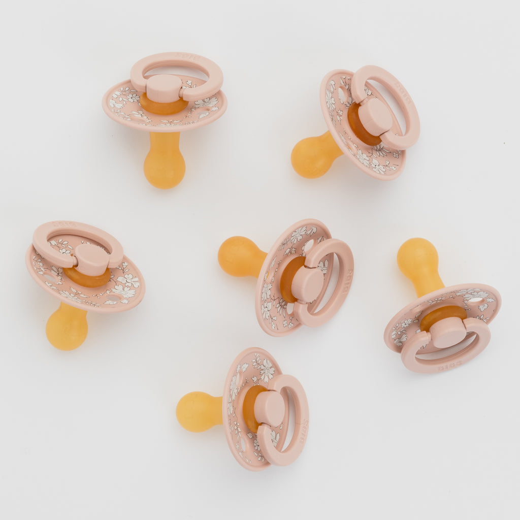 Set of six pink and yellow baby pacifiers on a white background