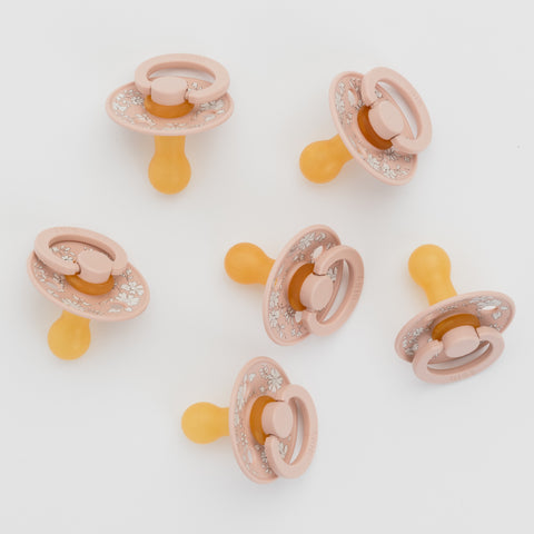 Set of six pink and yellow baby pacifiers on a white background