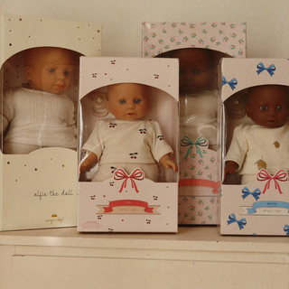 Four dolls in packaging with different skin tones on a shelf.