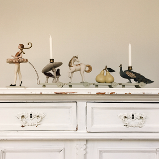 Decorative candle holders shaped like animals on a white dresser.
