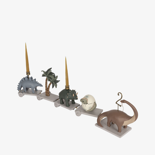 Set of dinosaur-themed candle holders on a white background