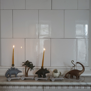 Decorative candle holders shaped like animals on a mantelpiece with white tiled wall in the background.
