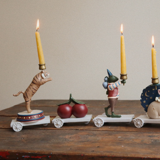 Decorative candle holders with figurines on a wooden surface