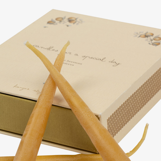 Two long candles in front of a box labeled 'Candles for a special day' on a white background.