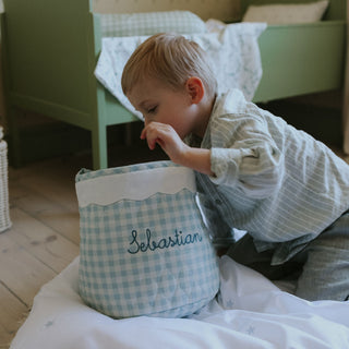 Child interacting with a blue checkered bag named 'Sebastian' in a bedroom setting.