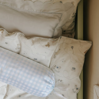 Set of decorative pillows with patterns on a bed with picnic gingham blue bolster pillow in front