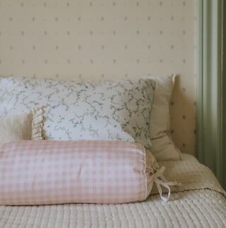 Bed with floral headboard and checkered pillow in a room with patterned wallpaper.