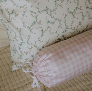 Floral-patterned pillow and pink checkered bolster on a textured surface