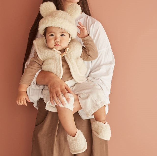 Child in booties behind held with a pink background