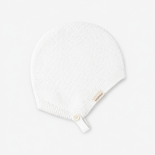 A white knit baby bonnet with a small button and a beige fabric tag that reads 'MarMar', shown on a light gray background.