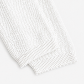 Close-up of a white ribbed knit fabric, showing the texture and cuff detail of baby pants.