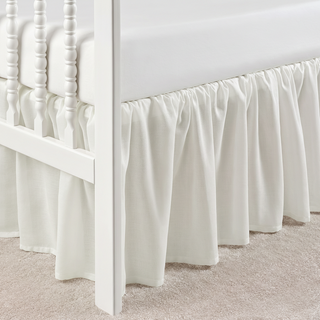 White bed skirt on a white bed frame with a neutral background
