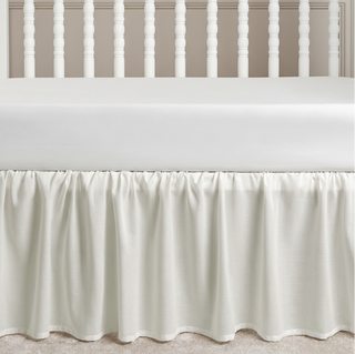White crib skirt on a crib with a neutral background