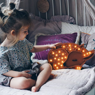 Little Lights Deer Lamp lit up on a bed