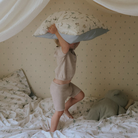 Dino Dreams Twin Set in Sage with little boy jumping on bed with a pillow in the air