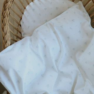 White baby blanket with subtle pattern draped over a wicker basket.