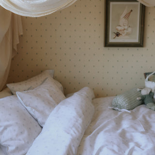 Bedroom with polka dot wallpaper, white bedding with blue floral print, and a framed picture on the wall.