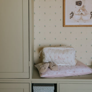 Children's room with a wardrobe, patterned wallpaper, and baby shoes on a changing table.