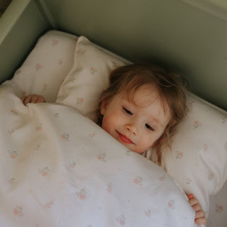 Child lying in bed with floral bedding and pillows
