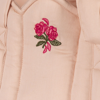 Embroidered roses on a beige quilted fabric background