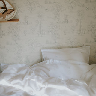 Bed with white bedding and blue embroidered stars against a textured wall.
