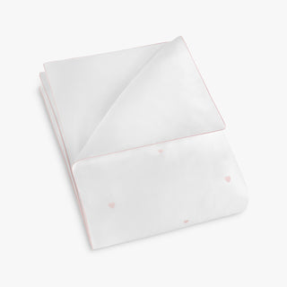 Folded white fabric with embroidered pink heart patterns on a white background