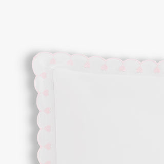 White pillow with pink heart patterns on a white background