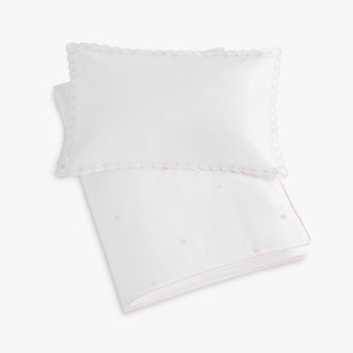 White pillow and toddler duvet with embroidered hearts patterns on a white background